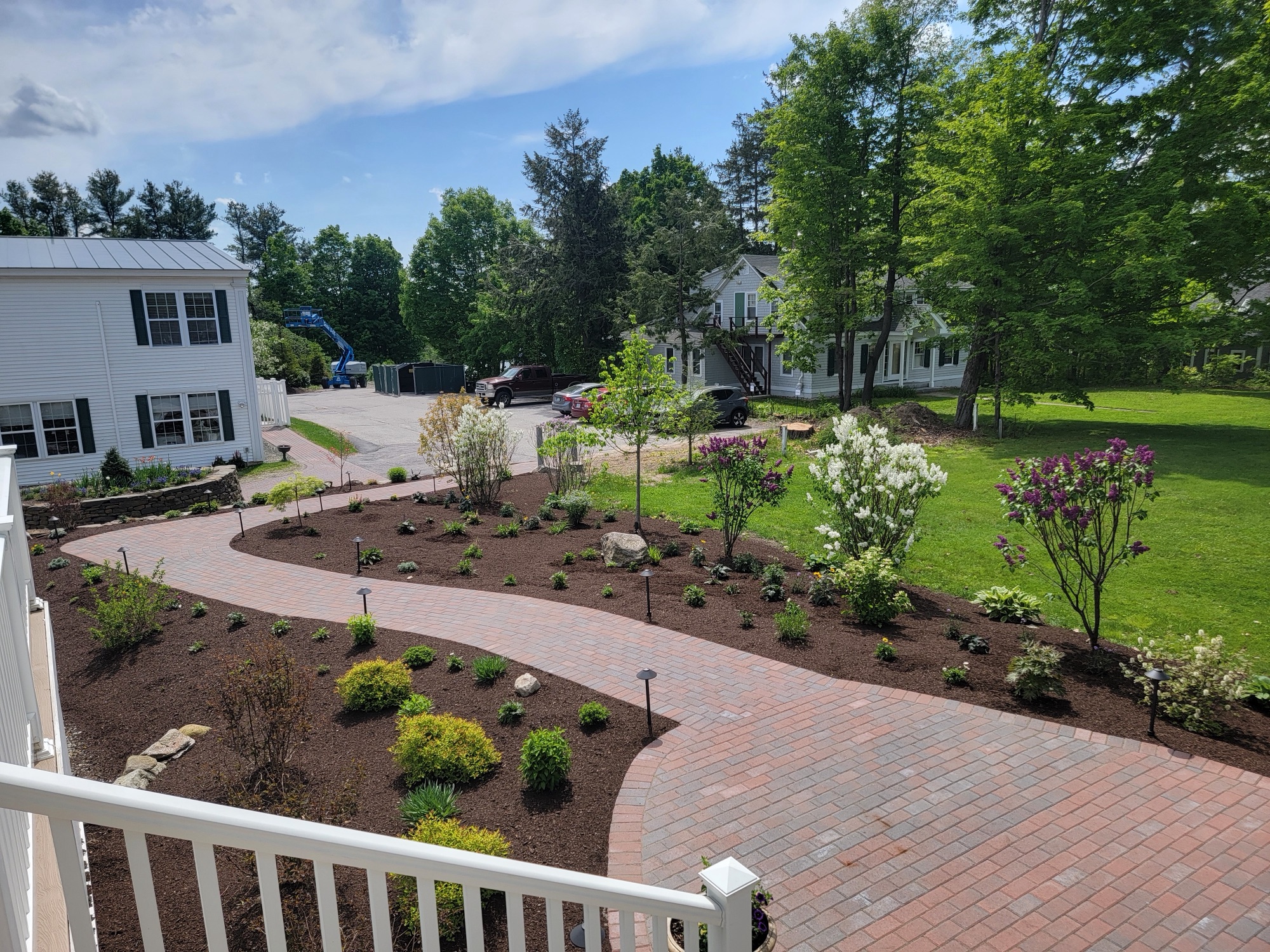 Landscaped property with paver patio, fence, and striped lawn