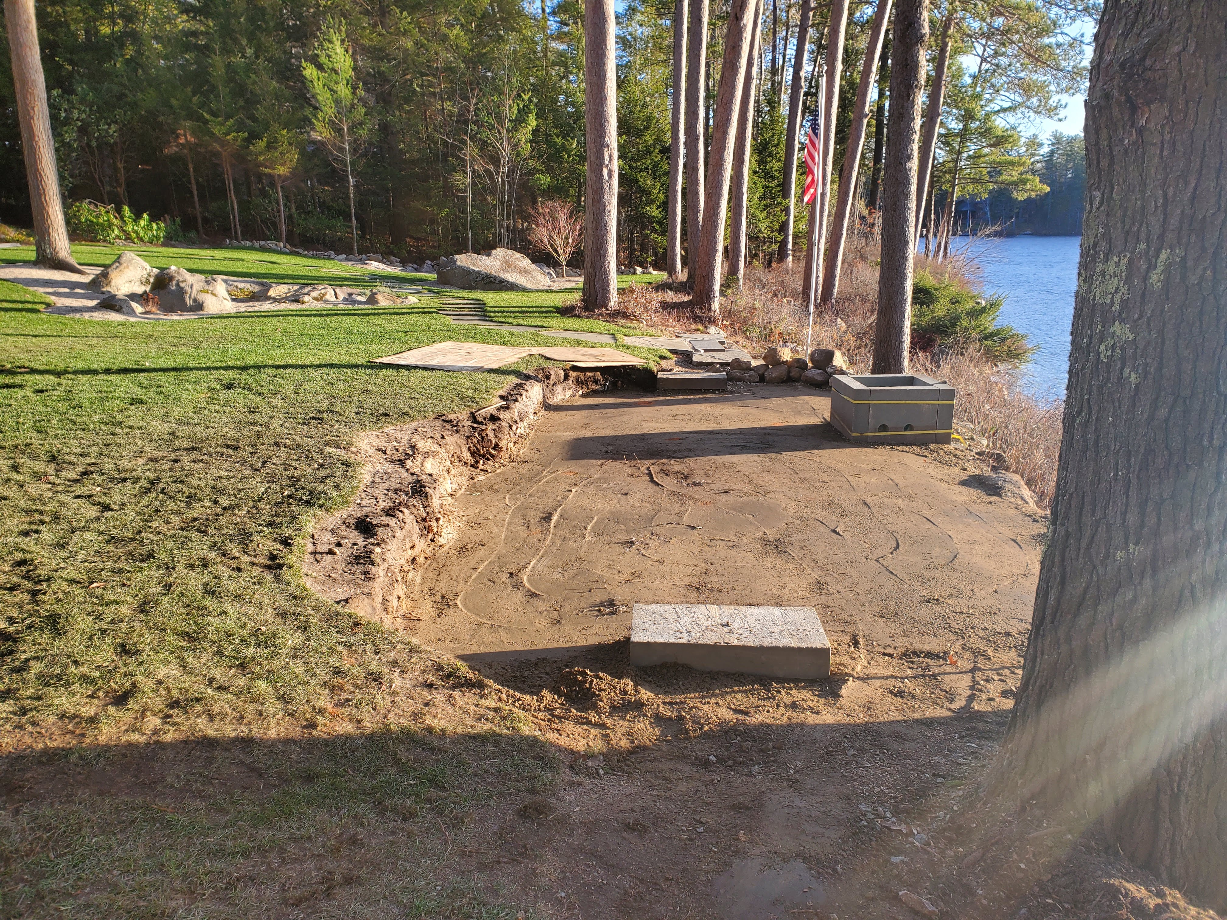 Dry-stack stone wall along a sandy lake shoreline at sunrise