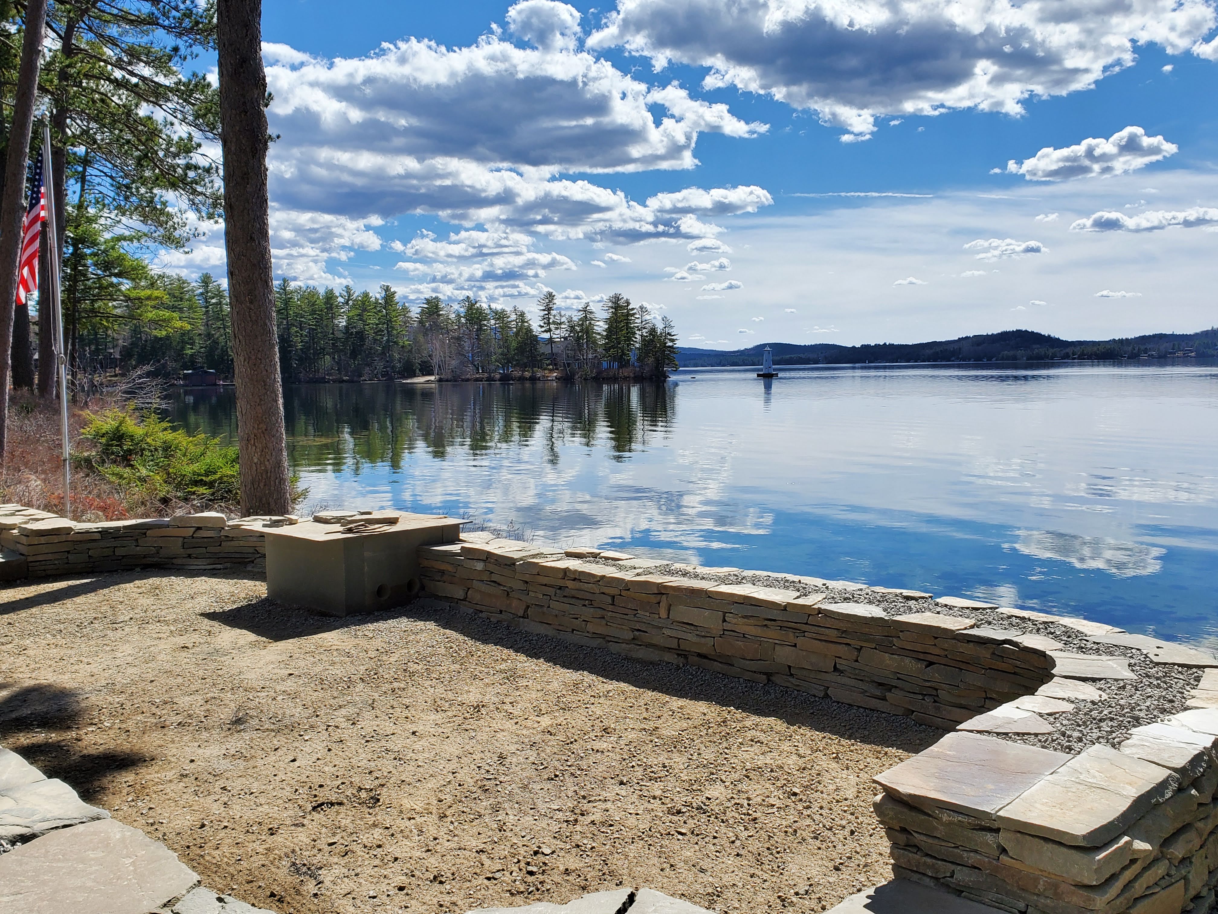 Finished stacked stone wall framing a beach and lake view with American flag