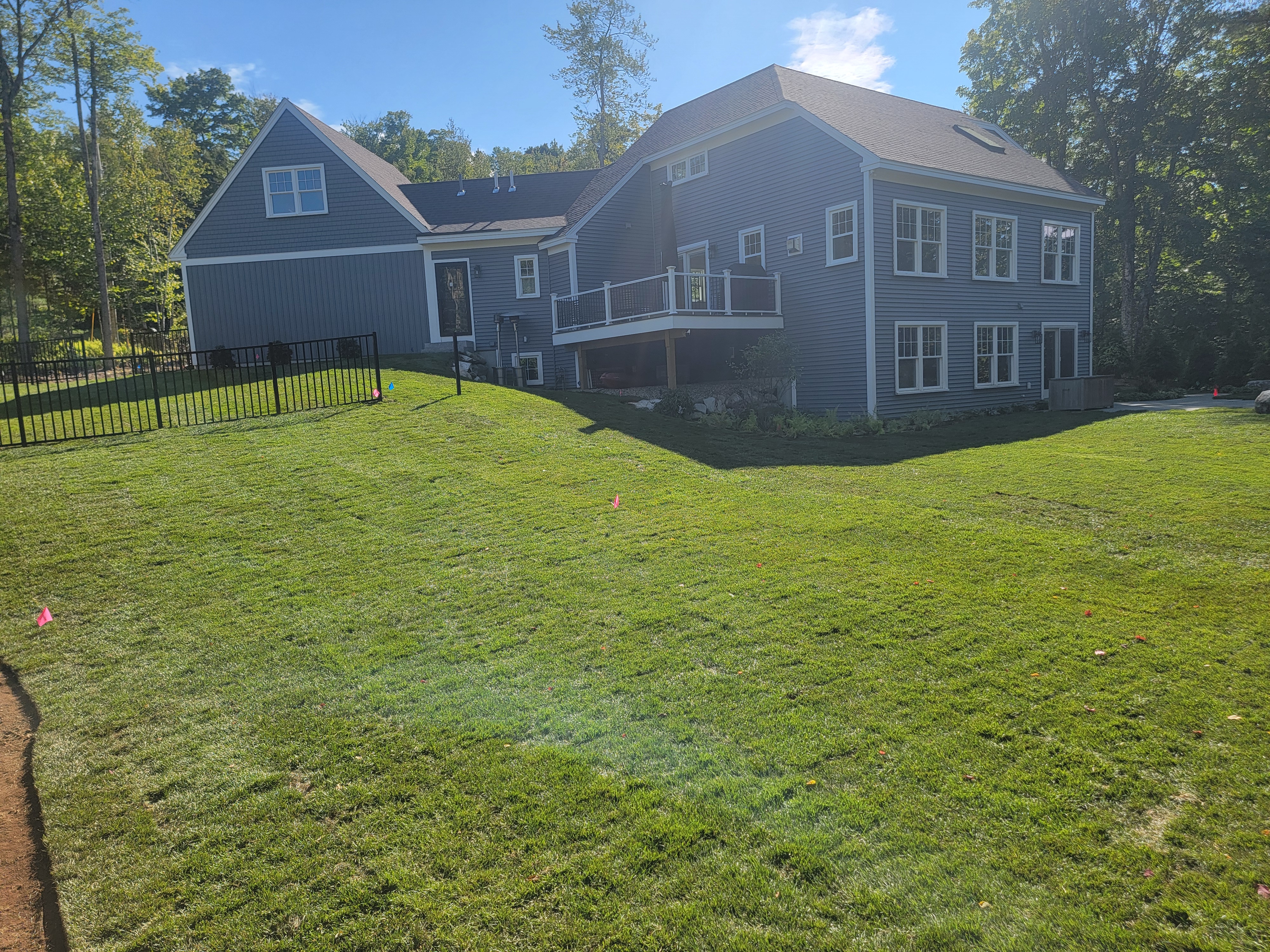 Freshly laid sod behind a navy-clapboard home with irrigation flags