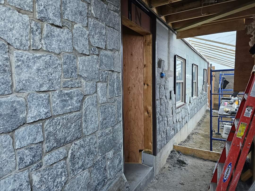 Gray cut-stone facade installed beside a wood door frame