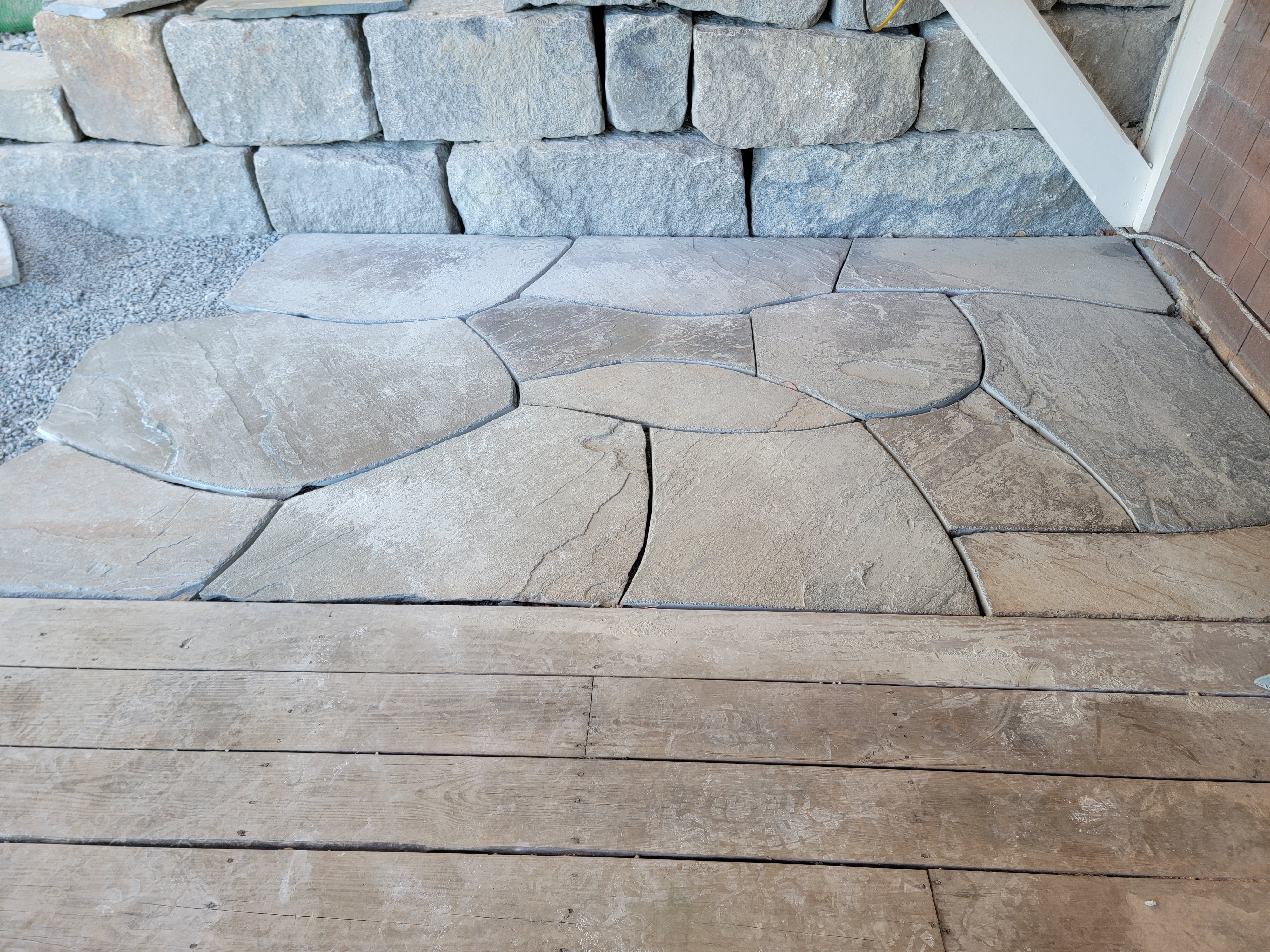 Flagstone landing meeting a stacked stone wall and wood deck