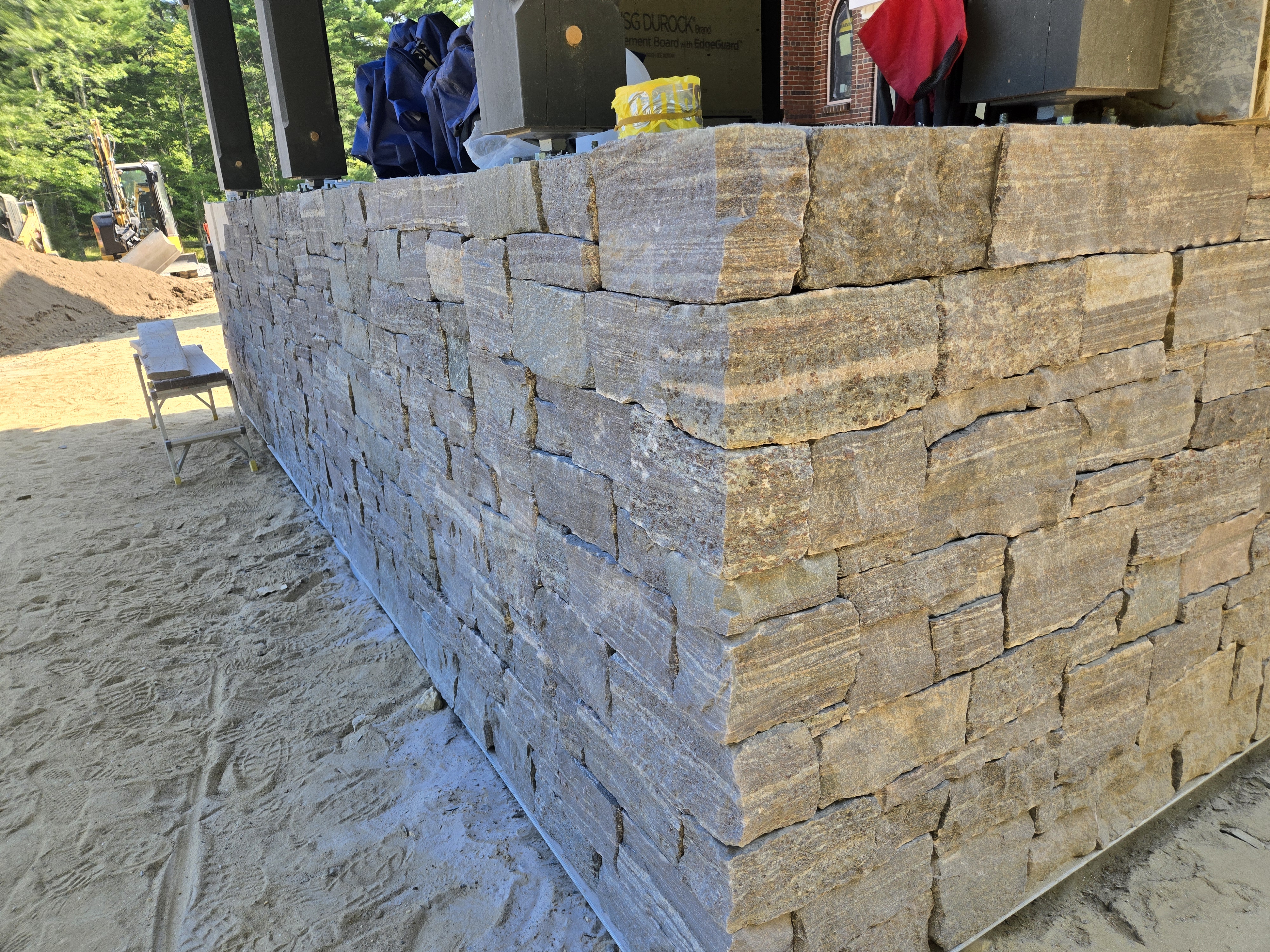 Tall stacked-stone wall under construction for an outdoor kitchen