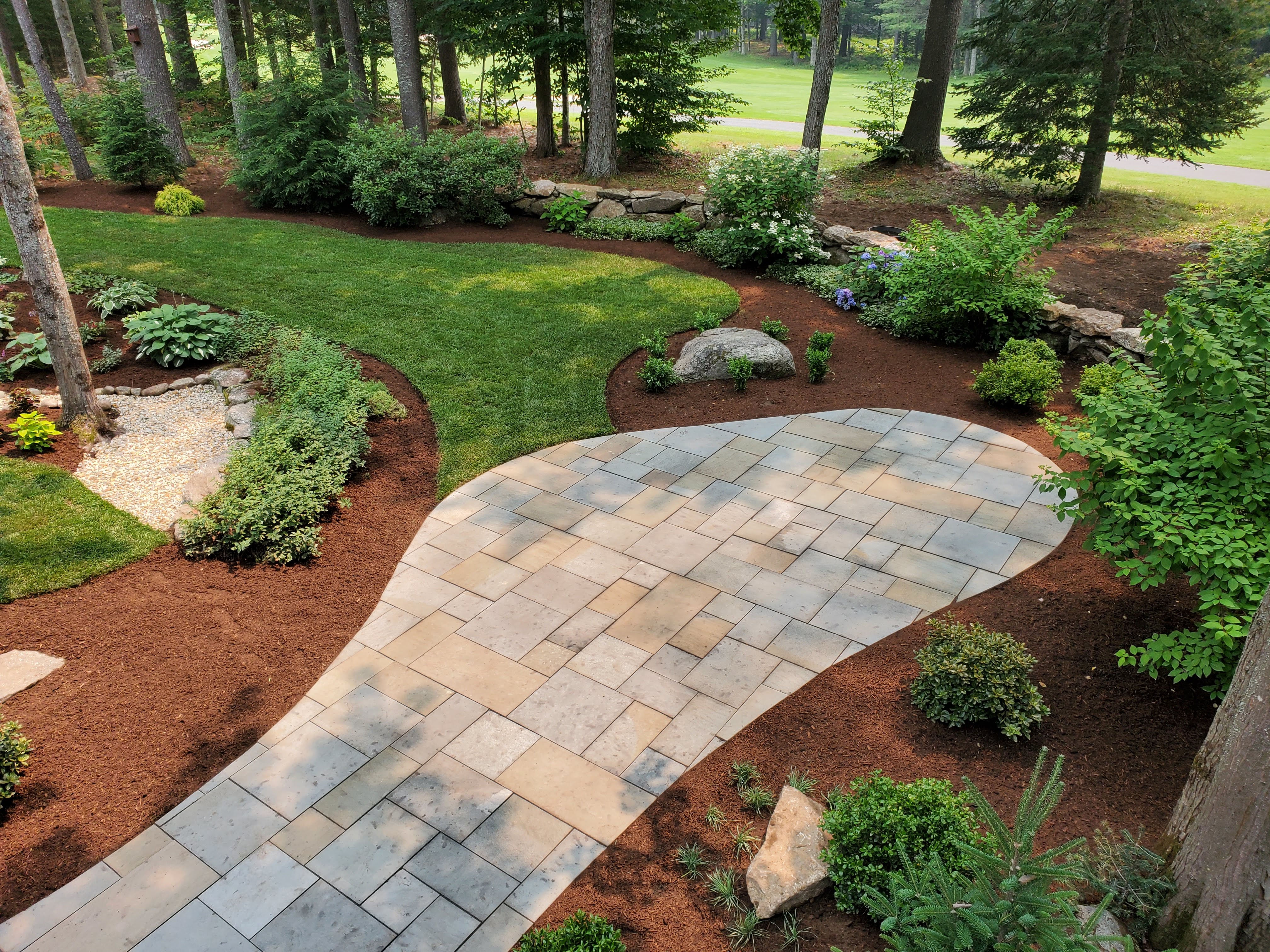 Finished curved bluestone patio in a landscaped backyard