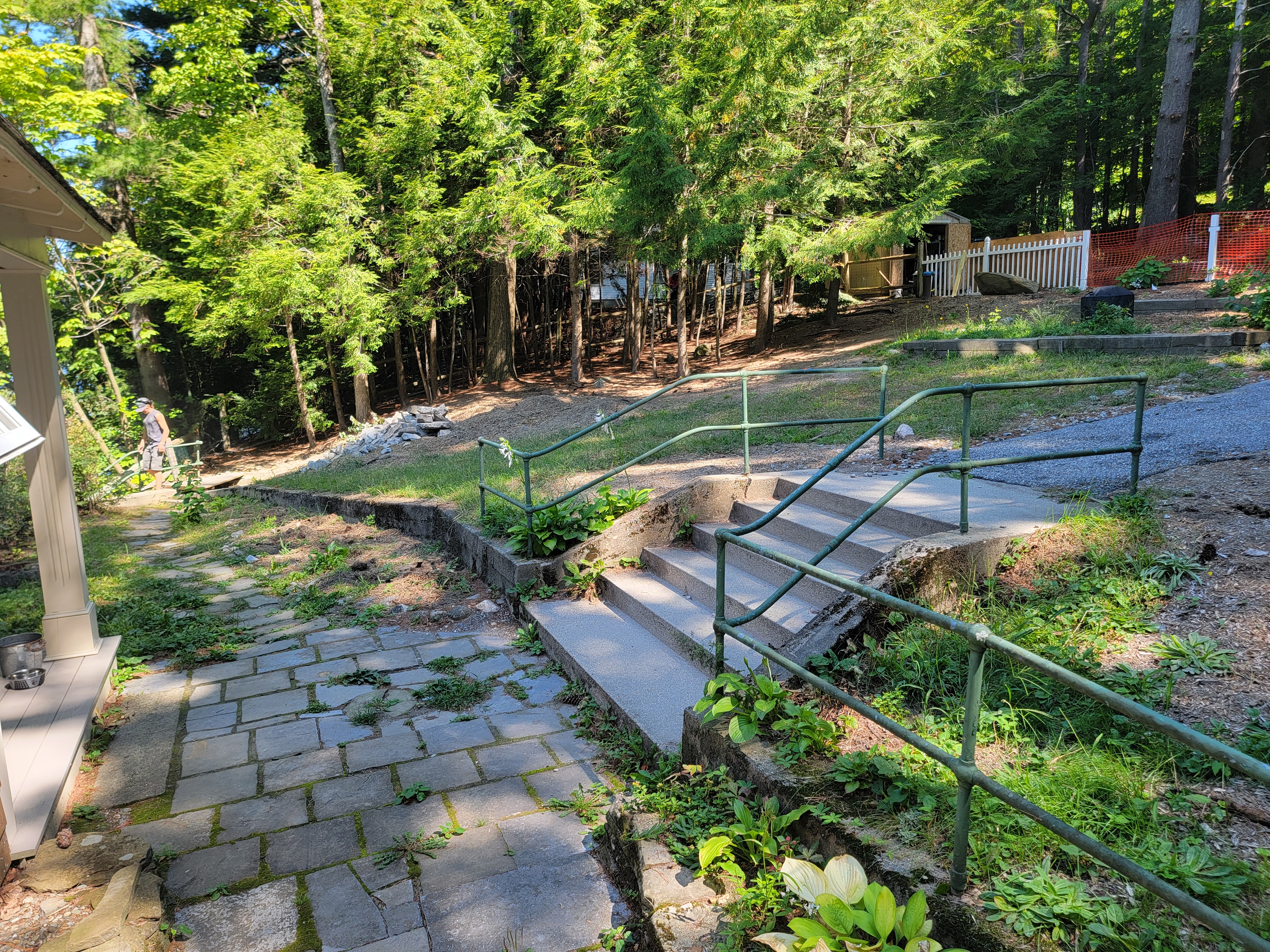 Old mossy concrete patio and steps with green metal handrail